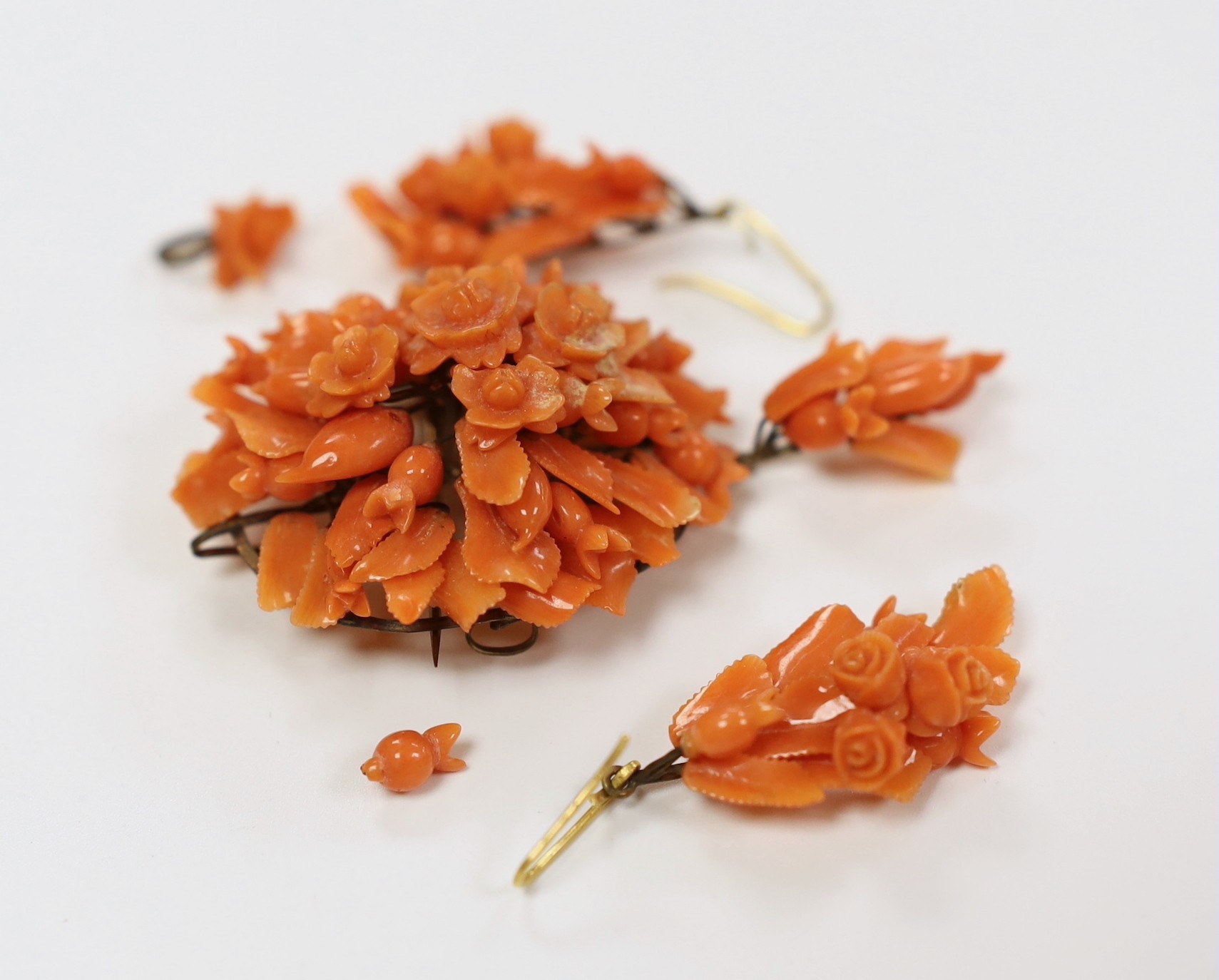 A late 19th/early 20th century gilt metal mounted drop pendant coral brooch carved as a bouquet of flowers, 68mm and a pair of similar earrings(a.f.)